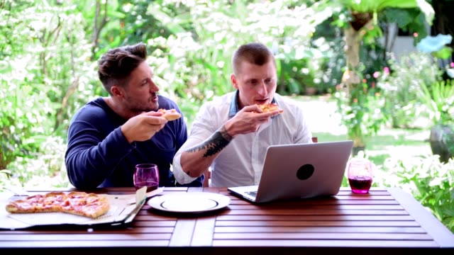 Gay-couple-having-pizza-for-lunch.-Convincing-talk.