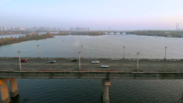 Luftbild-Autoverkehr-auf-Flussbrücke-am-Abend