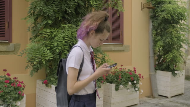 Beautiful-student-teenager-girl-with-smartphone-reading-and-writing-text-message,-smiling-on-city-street