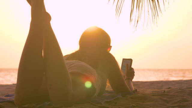 CLOSE-UP:-Tourist-Mädchen-genießt-Sommerabend-am-Strand-durch-Fummeln-mit-ihrem-Handy