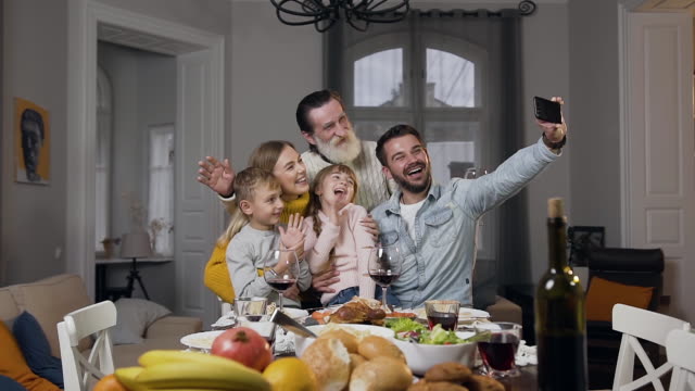 Atractiva-familia-feliz-saludando-las-manos-mientras-hace-selfie-en-el-banquete-de-la-familia