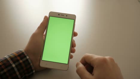 Man-using-cell-phone.-Male-holding-a-smartphone-in-the-hands-of-a-green-screen-green-screen,-hand-of-man-holding-mobile-smart-phone-with-chroma-key-green-screen-on-white-background.