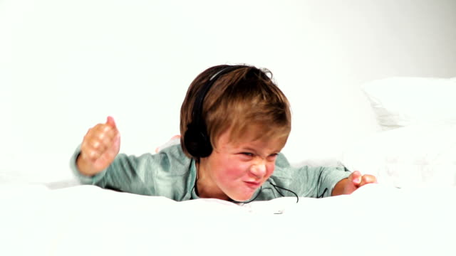 4-jähriger-bub-im-bett-mit-kopfhörern-spielt-mit-dem-la-tableta