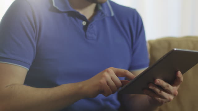 Man-Sitting-on-Couch-and-Using-Tablet