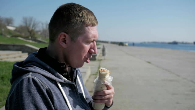 Portrait-of-man-in-a-wheelchair-close-up-eats-shawarma,-lonesome-disabled-man