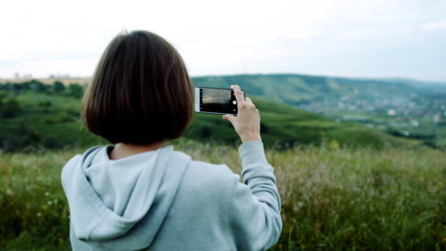 Frau-nimmt-eine-schöne-Landschaft-auf-Kamera-Handys.