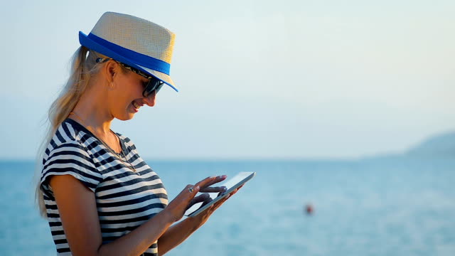 Girl-tourist-communicates-in-social-networks-on-the-tablet-in-a-trip-by-the-sea