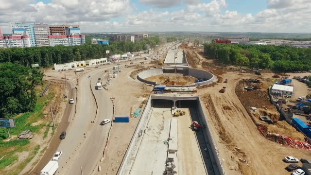 huge-traffic-roundabout-under-construction-and-long-road,-aerial-shot,-drone-is-flying-along