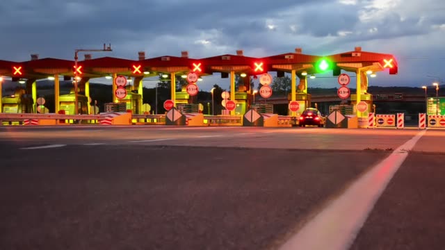 Time-lapse-of-Highway-Car-Paytoll-at-sunrise,-Night-lights-and-Autos-passing-through-toll-booths,-pay-for-using-highway-and-motorway
