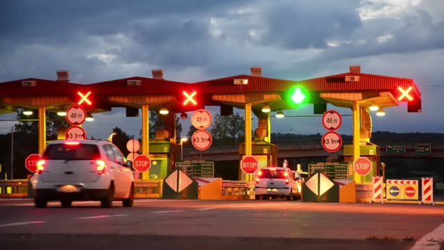 Carretera-coche-Paytoll-en-el-amanecer,-las-luces-de-noche-y-Autos-pasando-por-cabinas-de-peaje,-pagar-por-usar-la-carretera-y-autopista