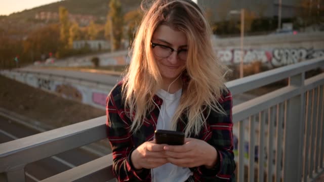 Hübsche-Teenager-Mädchen-nutzt-ihr-Smartphone-bei-Sonnenuntergang