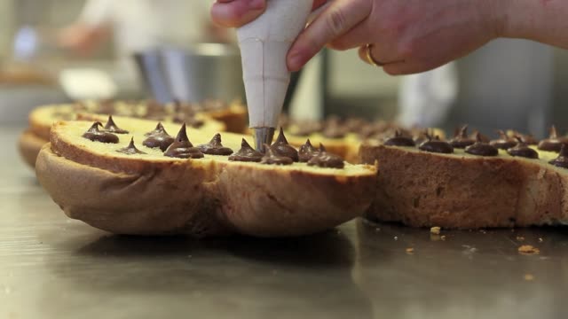 Pastry-Chef-Hände-gefüllt-Osterkuchen-süßes-Brot-mit-Schokolade,-Nahaufnahme-auf-der-Arbeitsplatte-in-der-Konditorei