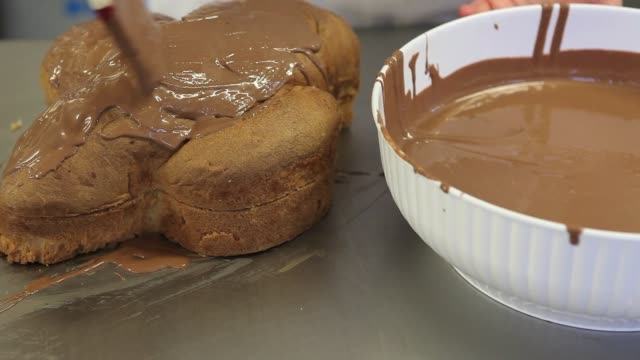 Pastry-Chef-Hände-glasiert-Osterkuchen-süßes-Brot-mit-Schokolade,-Nahaufnahme-auf-der-Arbeitsplatte-in-der-Konditorei