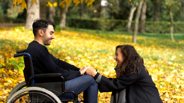 Mann-im-Rollstuhl-mit-seiner-Freundin-lächelt-im-park