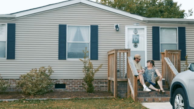 Man-and-woman-sitting-on-their-steps-of-their-manufactured-home-talking-together