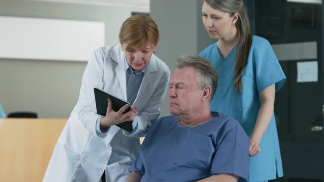 En-el-Hospital-femenino-médico-muestra-Tablet-PC-al-paciente-mayor,-explicando-su-condición.-Moderno-Hospital-con-la-mejor-atención-posible.