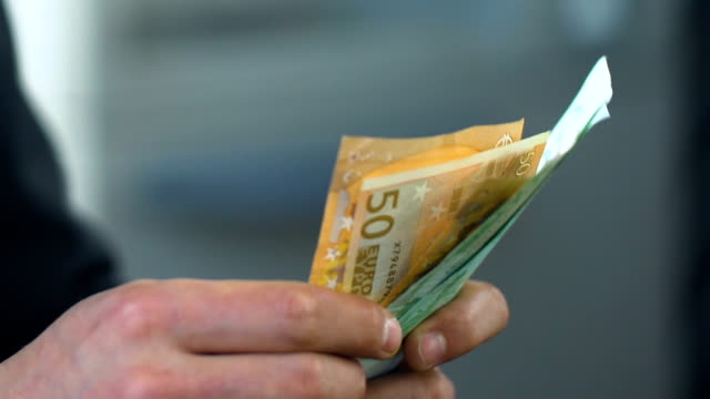 Hombre-contando-cerca-euros,-recibiendo-dinero-de-subsidio-social-en-Banco,-negocio