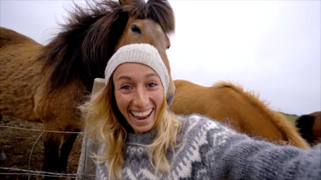 Blondes-Haar-Mädchen-in-Island-unter-Selfie-Porträt-mit-Islandpferd-in-grüne-Wiese.-Im-Frühling,-Bewölkter-Himmel,-Frau-trägt-isländischen-grau-wolle-Pullover-gedreht.-Die-Leute-reisen-tierischen-Zuneigung-Konzept-Zeitlupe
