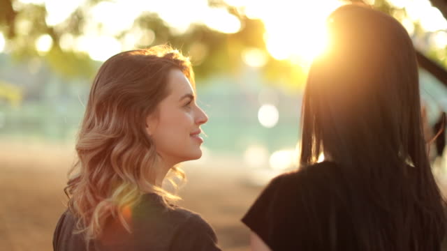Girl-looking-at-her-friend-during-sunset-golden-hour-sunset-time-with-sunklight-flare.-Female-friends-together-at-the-park