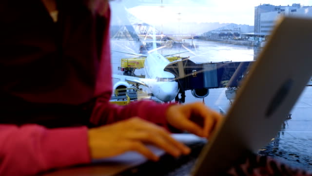 Frau-Hand-tippt-auf-einem-Laptop-am-Fenster-auf-einem-Flughafen-auf-dem-Hintergrund-einer-Flugzeug-Nahaufnahme
