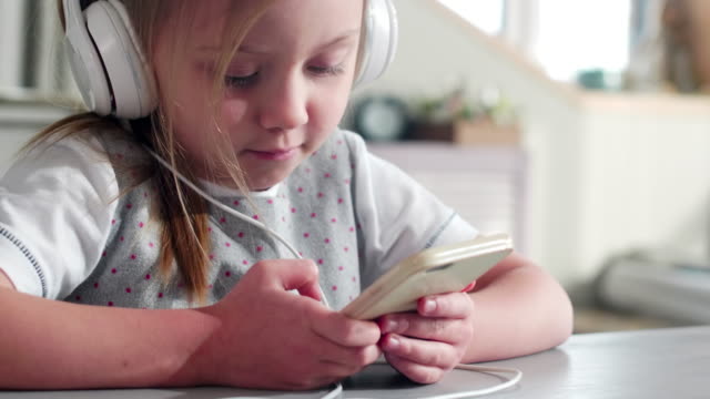 Niedliche-kleine-Mädchen-anhören-von-Musik-auf-Smartphone