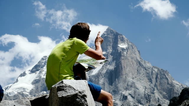 Touristischen-Mann-Wanderer-Blick-auf-die-Karte-und-die-Strecke-in-den-Bergen-sitzen-auf-den-Rock-close-up,-Slow-motion
