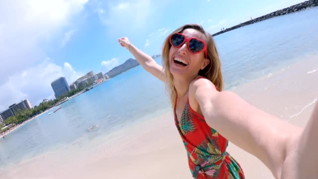 Selfie-von-Mädchen-mit-Herz-geformt-Sonnenbrille-am-Strand-von-Hawaii.-Junge-Frau,-die-eine-Selfie-am-Strand-von-Waikiki-in-Honolulu.-Hawaii-USA