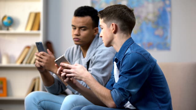 Adolescentes-afroamericanos-y-caucásicos-que-desplazan-smartphones,-adicción-a-gadgets