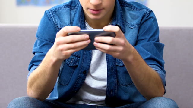 Entranced-teenager-playing-fast-paced-video-game-on-smartphone,-leisure-time