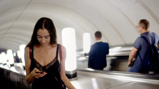 Schönheitsfrau-auf-Rolltreppe-in-U-Bahn-oder-U-Bahn-lesen-Nachricht-in-Telefon-Lächeln