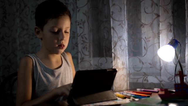 Niño-utiliza-tableta-para-estudiar,-niño-escribiendo-tarea-en-la-noche-uso-de-Internet-FullHD