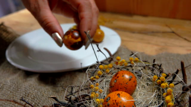 Female-hand-takes-quail-eggs-from-a-white-plate