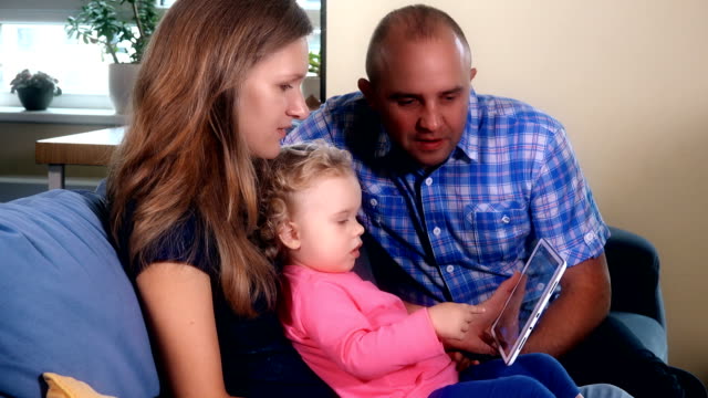 Familienmitglieder-haben-Spaß-mit-Tablet-auf-Sofa