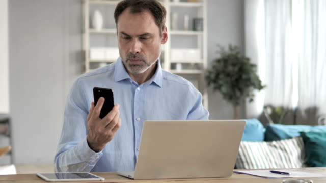 Old-Businessman-Using-Smartphone-at-Work