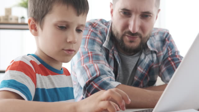 Boy-aprendiendo-a-usar-el-ordenador-portátil-con-el-padre-en-casa