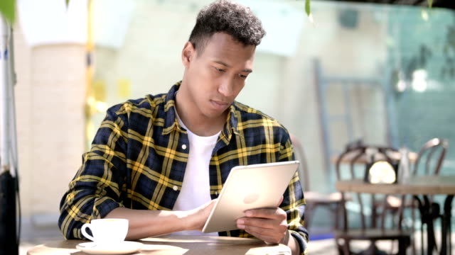 Young-African-Man-Using-Tablet,-Outdoor-Cafe