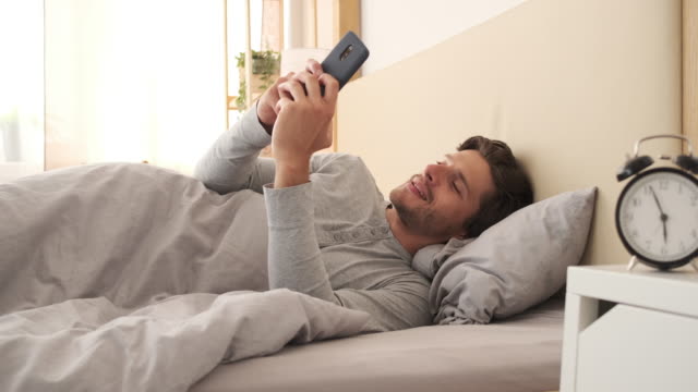 Man-using-mobile-phone-in-bed