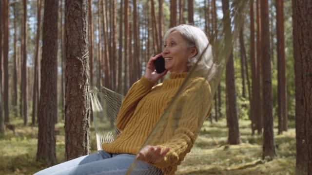 Old-Woman-Sitting-in-Hammock-Outdoors