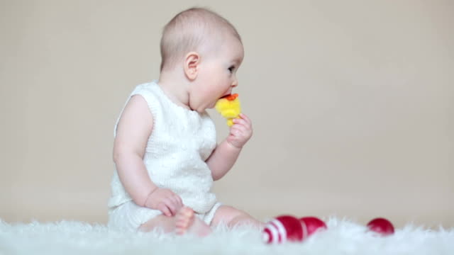 Lindo-niño-pequeño-niño,-jugando-con-huevos-de-pascua-de-colores-y-patos-decorativos-pequeños,-tiro-aislado,-fondo-beige