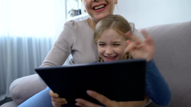 Joyful-cute-girl-and-mother-touching-tablet-screen-and-smiling-playing-game,-fun