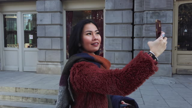 Mujer-asiática-tomando-fotos-por-la-cámara-del-teléfono-móvil-en-la-calle-Europa