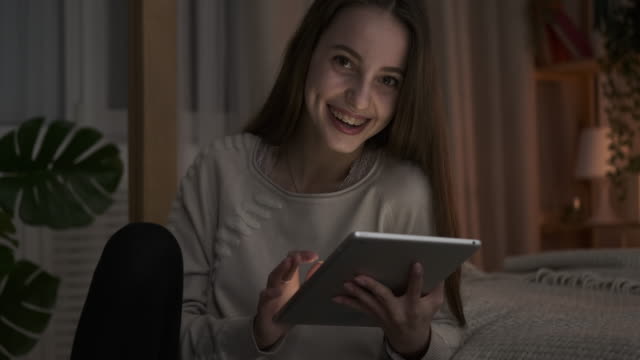 Adolescente-chica-divirtiéndose-usando-tableta-digital-por-la-noche