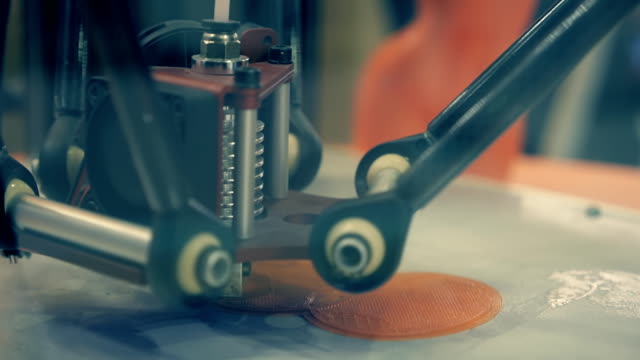 3-D-Drucker-druckt-aus-orangenem-Kunststoff-die-Abbildung-von-einem-nackten-Mädchen.-Close-up