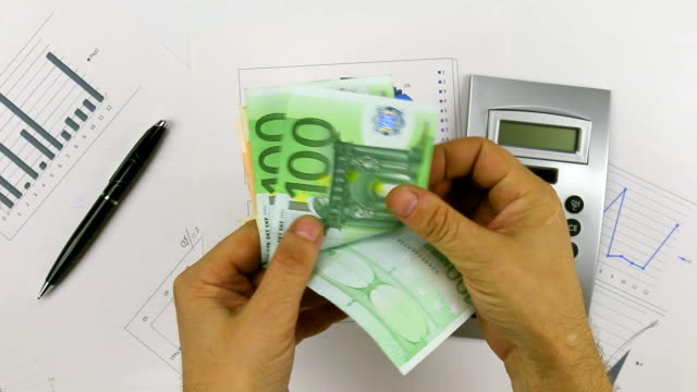 Contando-euros-en-un-fondo-de-una-calculadora-y-un-bolígrafo