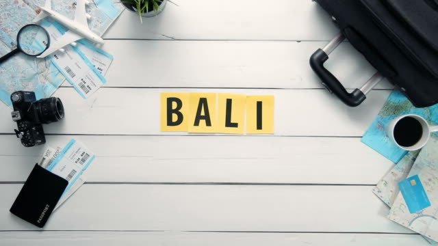 Draufsicht-Zeitraffer-Hände-auflegen-weißen-Schreibtisch-Wort,-das-"BALI"-mit-Reisen-Gegenständen-dekoriert