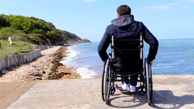 Rückseite-des-behinderten-Menschen-im-Rollstuhl-am-Strand