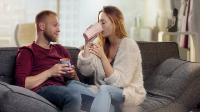 Dulce-pareja-de-jóvenes-bebiendo-té-en-sofá