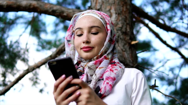 Chica-musulmana-utilizando-el-teléfono-móvil-en-el-Parque