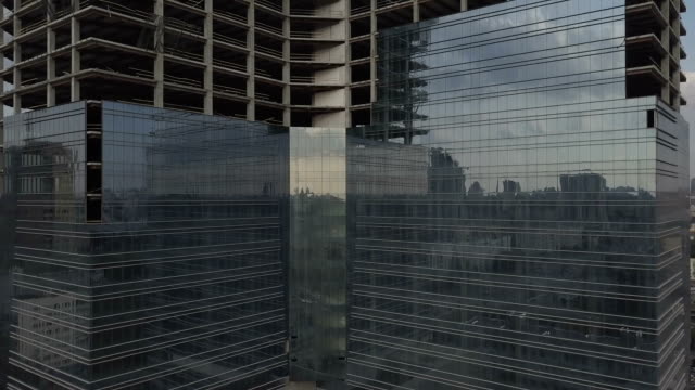 Skyscraper-with-a-glass-facade-near-the-old-multi-apartment-building.-The-camera-moves-from-the-new-building-to-the-old-house.-Aerial-view