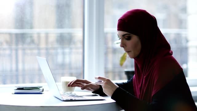 Attraktive-muslimisches-Mädchen-wird-einige-Informationen-von-der-Visitenkarte-auf-Laptop-Tastatur-eingeben.-Im-Innenbereich-Filmmaterial